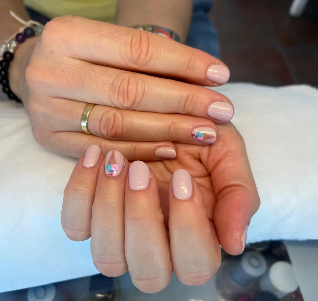 Manicura en tono nude con pequeños detalles de colores, trabajo de Estética Vintage Spa